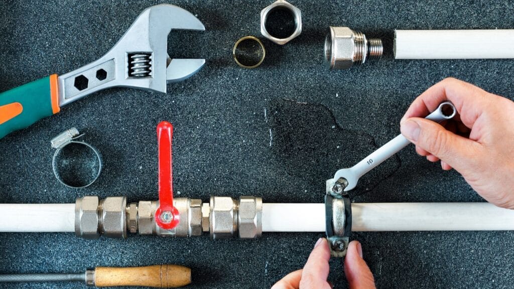 Plumber repairing a pipe valve with an adjustable wrench in Duluth