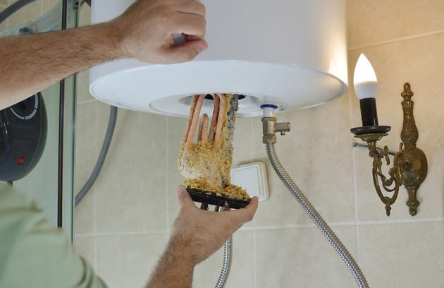 Technician removing mineral buildup from a water heater in Duluth