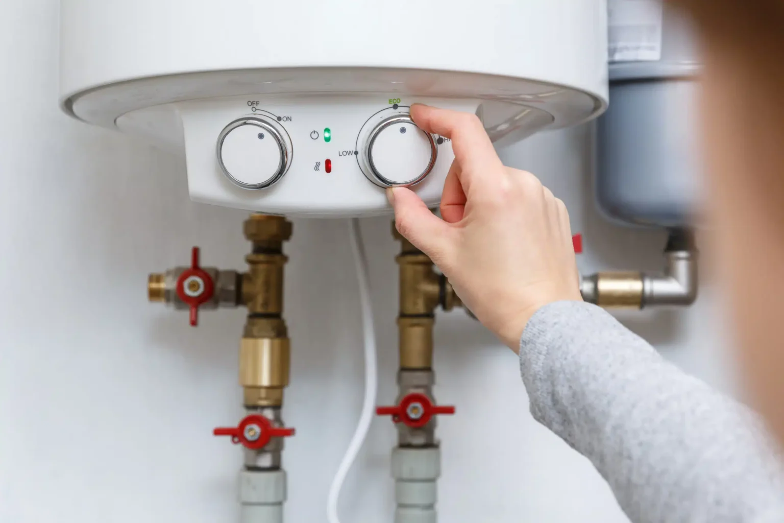 Homeowner adjusting the temperature controls on a water heater in Duluth